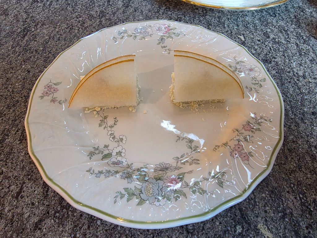 A decorative plate with a slice of dessert featuring a smooth texture and golden accents.