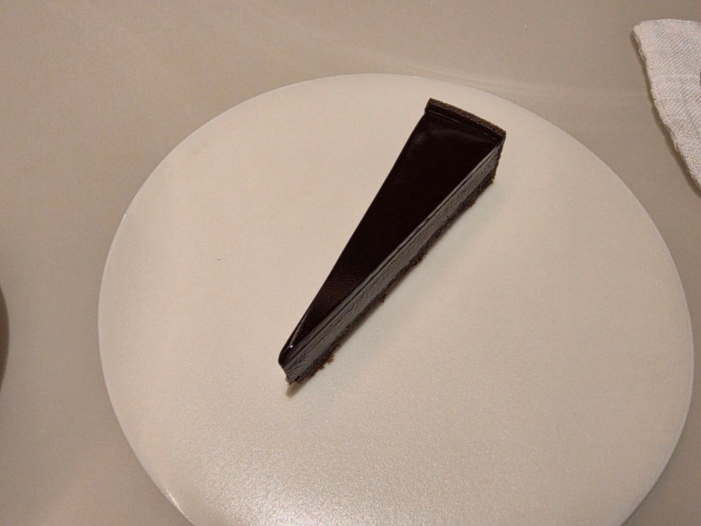A slice of chocolate cake on a white plate.