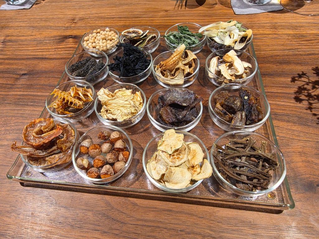 A selection of various dried herbs and spices displayed in small glass bowls on a wooden table.